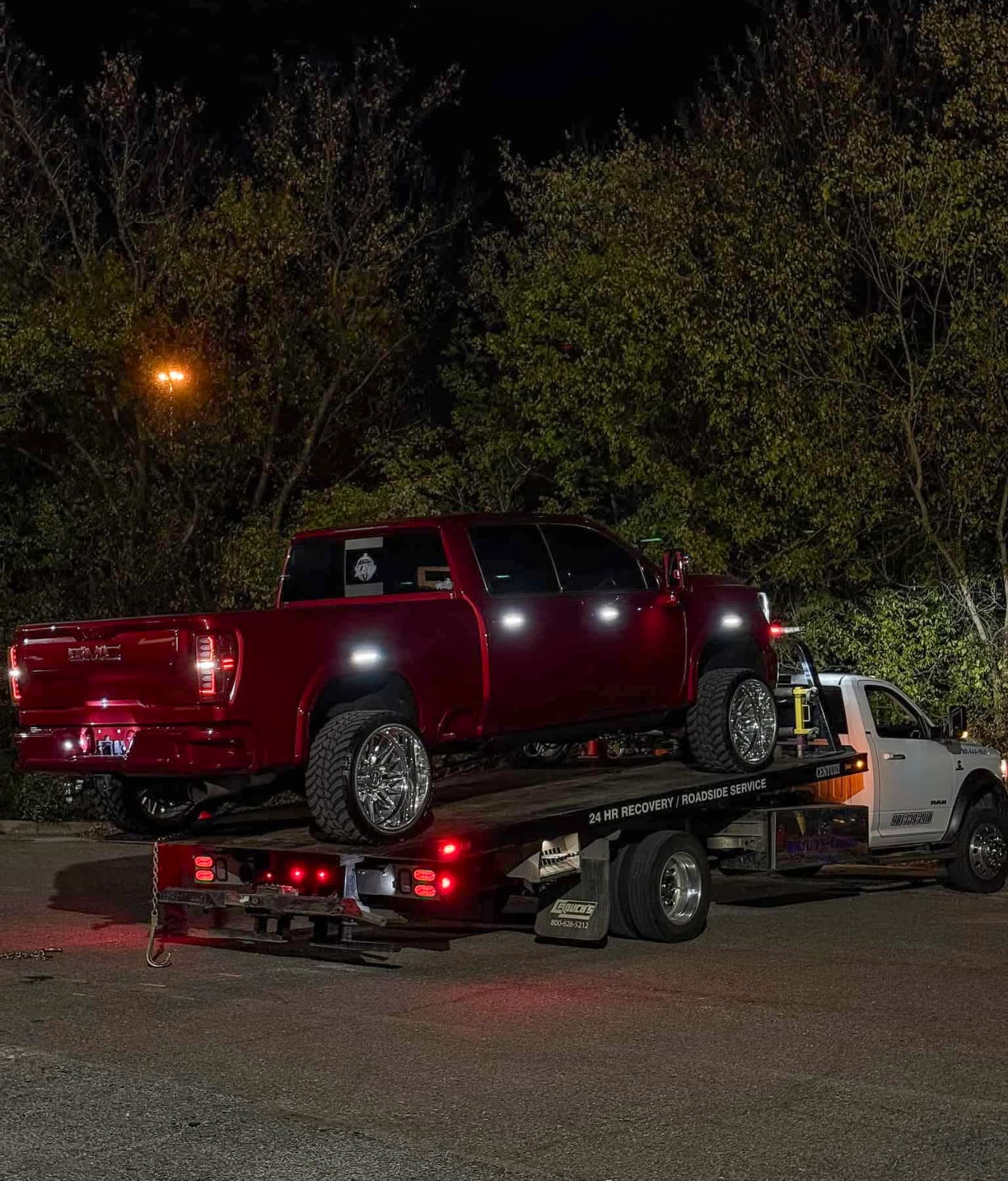 Smiths Towing flatbed hauling a red GMC pickup truck on a late-night call in the Cordova, TN area
